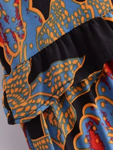 Close-up of vibrant bohemian floral pattern and tiered ruffle details on cotton dress