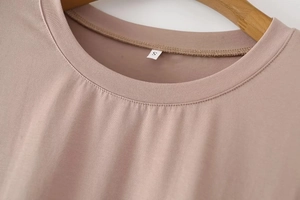 Close-up of the ribbed crew neck and size S label on a dusty pink Y2K style t-shirt