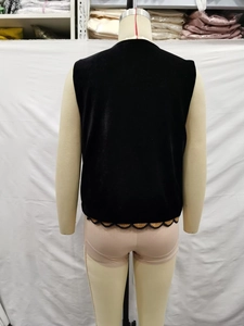 Détail du dos d'un gilet en velours noir avec bordure en dentelle dorée ondulée