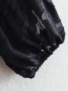 Makro-Detail des schwarzen Jacquard-Stoffs mit elastischem Puffärmel-Bündchen