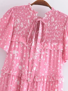Détail de la robe rose à fleurs avec poitrine smockée et col montant à volants