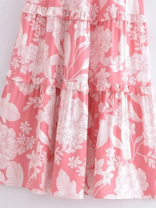 Detail of tiered ruffled hem on pink floral rayon summer dress with white blossoms
