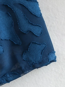 Macro detail of dark blue jacquard fabric with unique frayed edges and texture