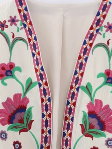 Detail of bohemian cream vest featuring vibrant floral embroidery and geometric borders