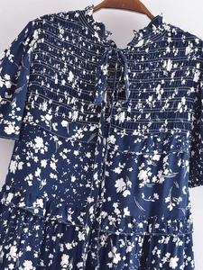 Détail du col smocké avec liens fins et imprimés floraux blancs sur robe d'été marine