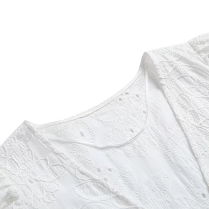 Détail de robe blanche avec broderie florale et texture de tissu à œillets respirante