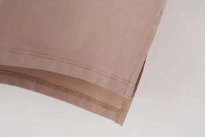 Detailed macro view of the double-needle stitching and overlock edge on brown knit fabric