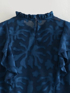 Detail of the navy blue blouse featuring sheer floral jacquard and ruffled stand collar
