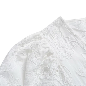 Vue macro détaillée de la broderie florale blanche sur une robe midi à volants
