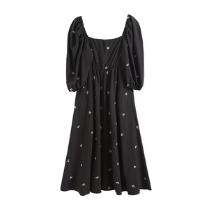 Detail of pink floral embroidery and puffed sleeves on black A-line summer dress