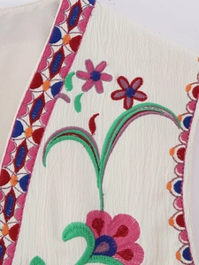 Close-up of bohemian floral embroidery on white sleeveless vest with detailed texture
