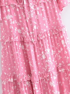 Détail d'une robe rose à fleurs avec volants étagés et lien à nouer à l'encolure