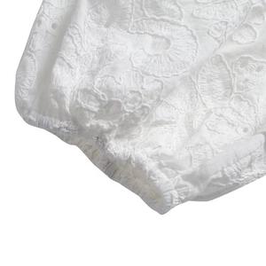 Détail d'une robe d'été blanche avec broderie florale et ourlet à volants élastiques