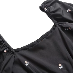Close-up of square neckline and floral embroidery on black puff sleeve dress