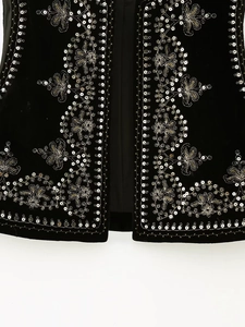 Detailed close-up of intricate silver and gold floral embroidery with sequins on black velvet