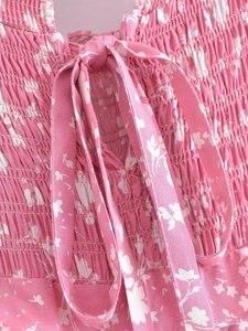 Détail de la robe fleurie rose avec design smocké sur la poitrine et nœuds au décolleté