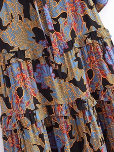 Detail view of tiered ruffles and blue bohemian floral print on black woven fabric