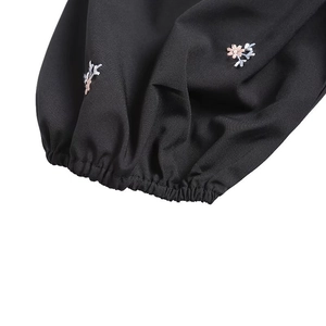 Detail shot of black dress sleeve with elastic cuff and delicate floral embroidery