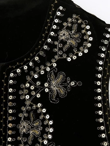 Macro view of sequin embroidery and floral vine patterns on black velvet fabric