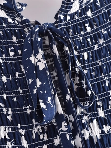 Détail du tissu floral bleu marine avec smocks élastiques et liens d'encolure