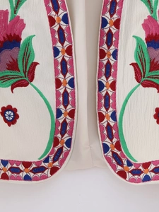Close-up of ethnic floral embroidery and geometric patterns on a sleeveless vest