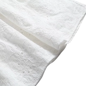 Détail macro de broderie anglaise florale blanche sur un tissu d'été raffiné