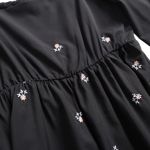 Detail of floral embroidery on black fabric with elastic smocked waist and soft pleats