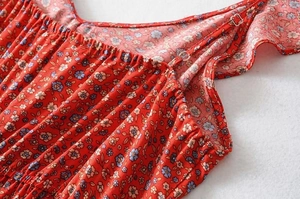 Detail of red floral dress with elastic ruffled neckline and adjustable thin straps