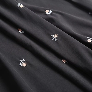 Detailed close-up of delicate floral embroidery on black loose-fit high-waisted dress