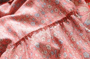 Detail shot of ruffle summer dress showing floral print fabric and neat red edge stitching