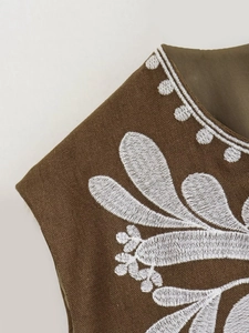 Detailed close-up of white floral embroidery on a vintage brown sleeveless vest jacket