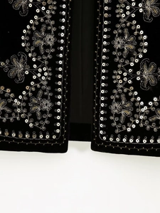 Macro detail of silver sequin embroidery on black velvet fabric with floral patterns