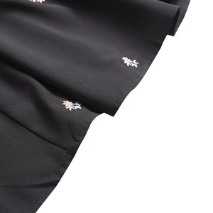 Detail of pink floral embroidery on black lightweight fabric of a Y2K summer midi dress