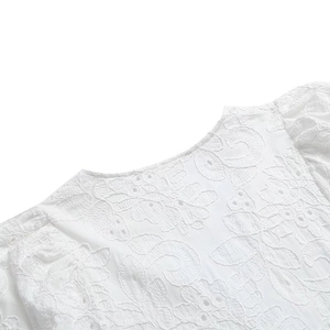 Détail de la broderie blanche et de la dentelle ajourée sur une robe longue d'été