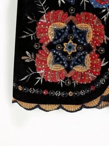 Broderie détaillée avec motifs floraux colorés et paillettes argentées sur gilet en velours