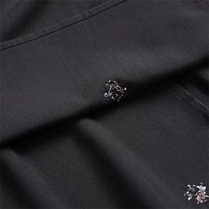 Macro shot of delicate floral embroidery on black fabric with subtle texture