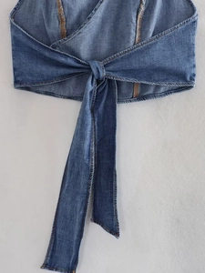 Detail of blue denim wrap top showing cross-tie design and orange contrast stitching