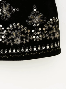 Detailed close-up of gold floral embroidery and metallic sequins on black velvet fabric