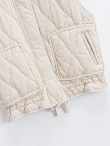Detail of quilted beige vest with wavy stitching, large pockets and adjustable drawstring hem