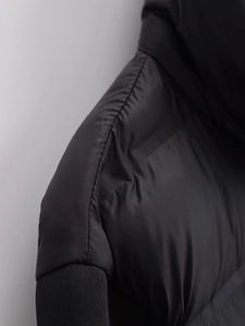 Detailed close-up of quilted stitching and ribbed knit cuffs on a black casual jacket