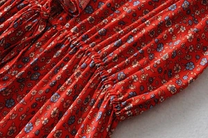 Macro detail of red floral print dress featuring ruffled edges and smocked waist texture