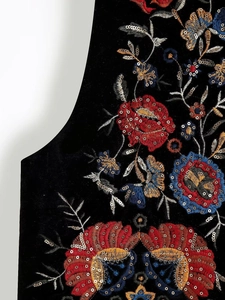 Détail de broderie florale et de paillettes argentées sur un gilet en velours noir