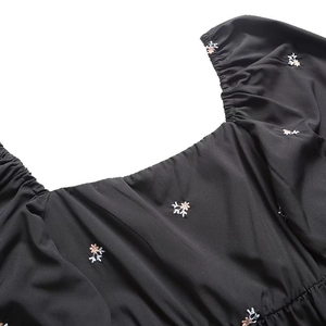 Detail of square neckline with floral embroidery and puffed sleeves on black dress