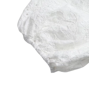 Détail de la broderie anglaise blanche complexe et dentelle ajourée sur une manche bouffante