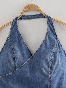 Detail of blue denim halter top featuring V-neck wrap design and contrast stitching