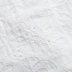 Gros plan détaillé de la broderie florale blanche et de la dentelle sur une robe midi