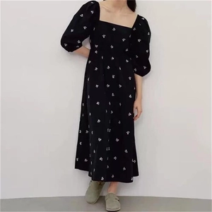 Detail of black summer dress with retro square neck, puff sleeves and white floral patterns