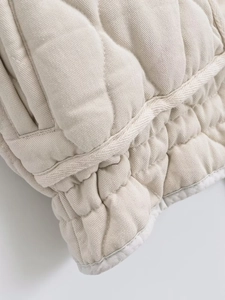 Close-up of quilted puffer vest fabric showing texture and elastic hem detail