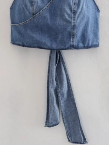 Detail of blue denim wrap top showing fabric texture, contrast stitching and long tie-up belt
