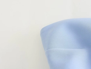 Close-up of light blue fabric texture showing detailed textile weave and soft material